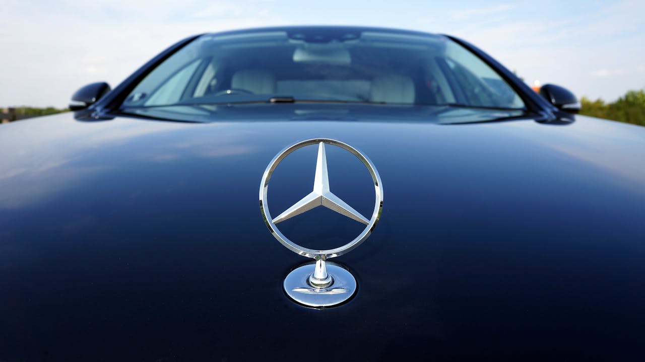 Close-up of a Mercedes-Benz emblem on a luxury car hood featuring a sleek design.