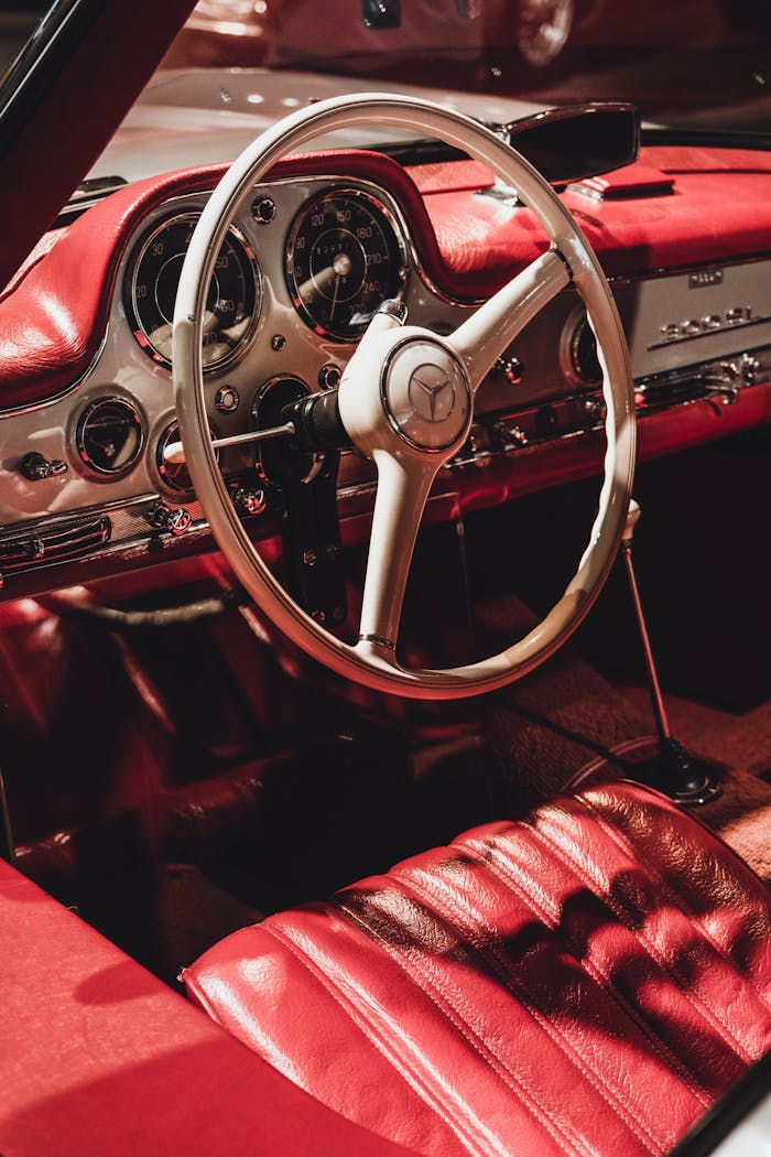 Vintage Mercedes car interior with red details and iconic steering wheel.